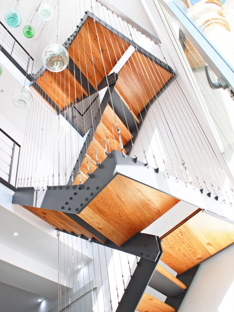 Escalera suspendida de acero y madera con tensores, rehabilitación de vivienda en Escaloncillos 6, Loja (Granada).