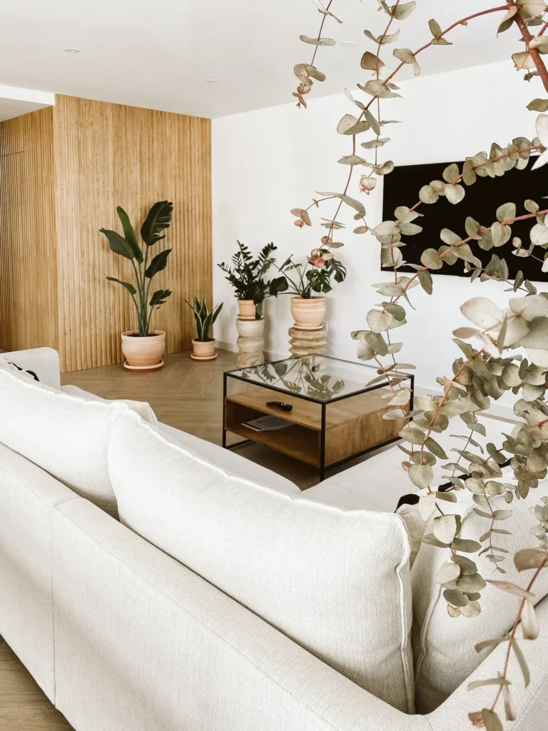 Vista del estar desde el sofá, con mesa de centro y frente de televisión revestido en tono madera.