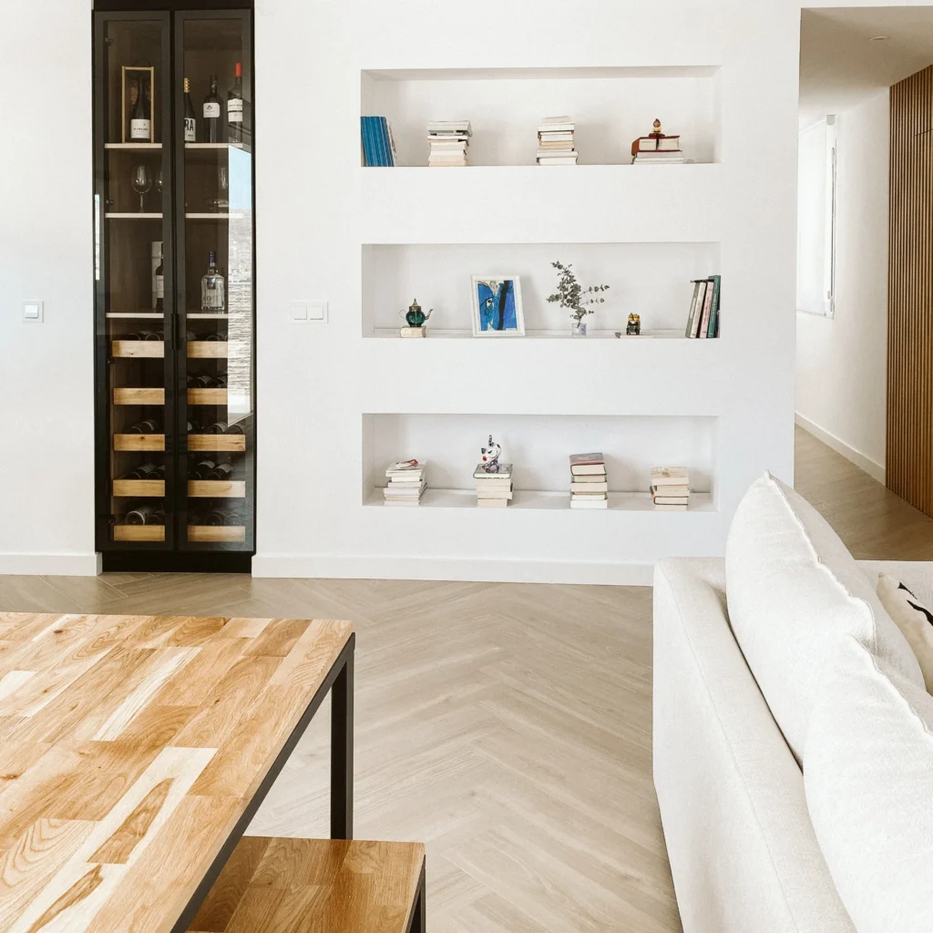 Estantería integrada junto a una vitrina, con la mesa del comedor y el sofá en primer plano.