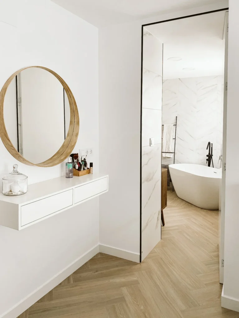 Tocador del dormitorio junto al paso acristalado hacia el baño, con bañera al fondo.